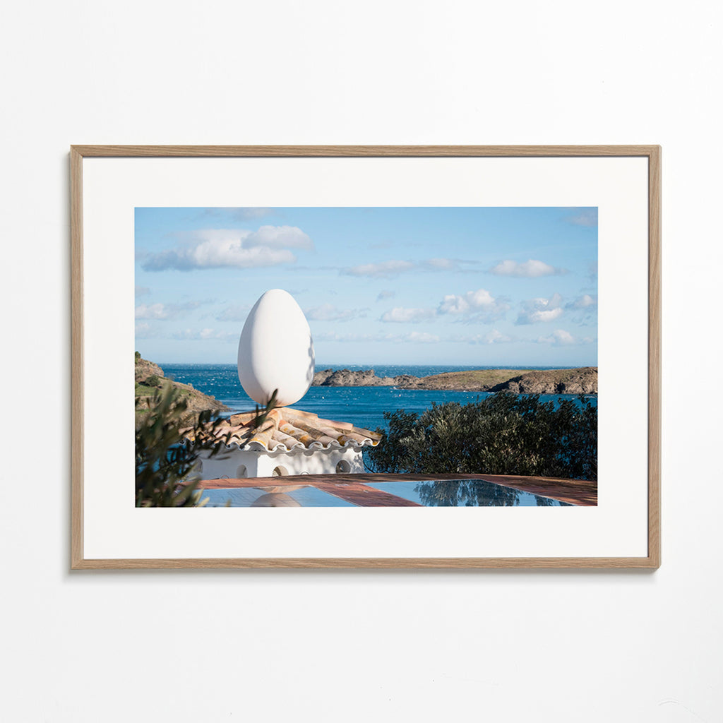 Landscape art featuring an egg sculpture by the sea