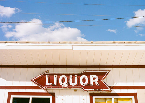 Cuadro vintage con rótulo 'LIQUOR' y cielo azul